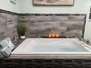 A spa-like bathroom with a large bathtub, a wooden wall, and decorative items. - Anysel Pool house (Orlando)
