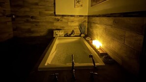 Una stanza spa con una vasca, decorazioni murali in legno e un tavolino con una candela.