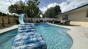 Una piscina con uno scivolo e lettini gonfiabili.