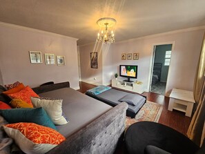 A modern living room with a sofa, a bed, a television, and a small table. - Anysel Pool house (Orlando)