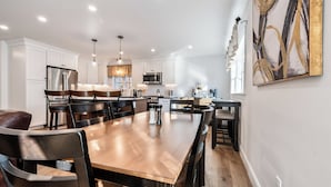 Una cocina moderna con armarios blancos, electrodomésticos de acero inoxidable y una mesa de comedor de madera.