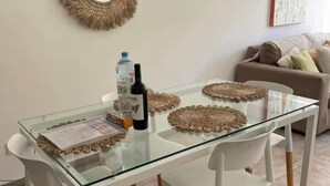 En matplats med ett glasbord, vita stolar och vävda bordsunderlägg.