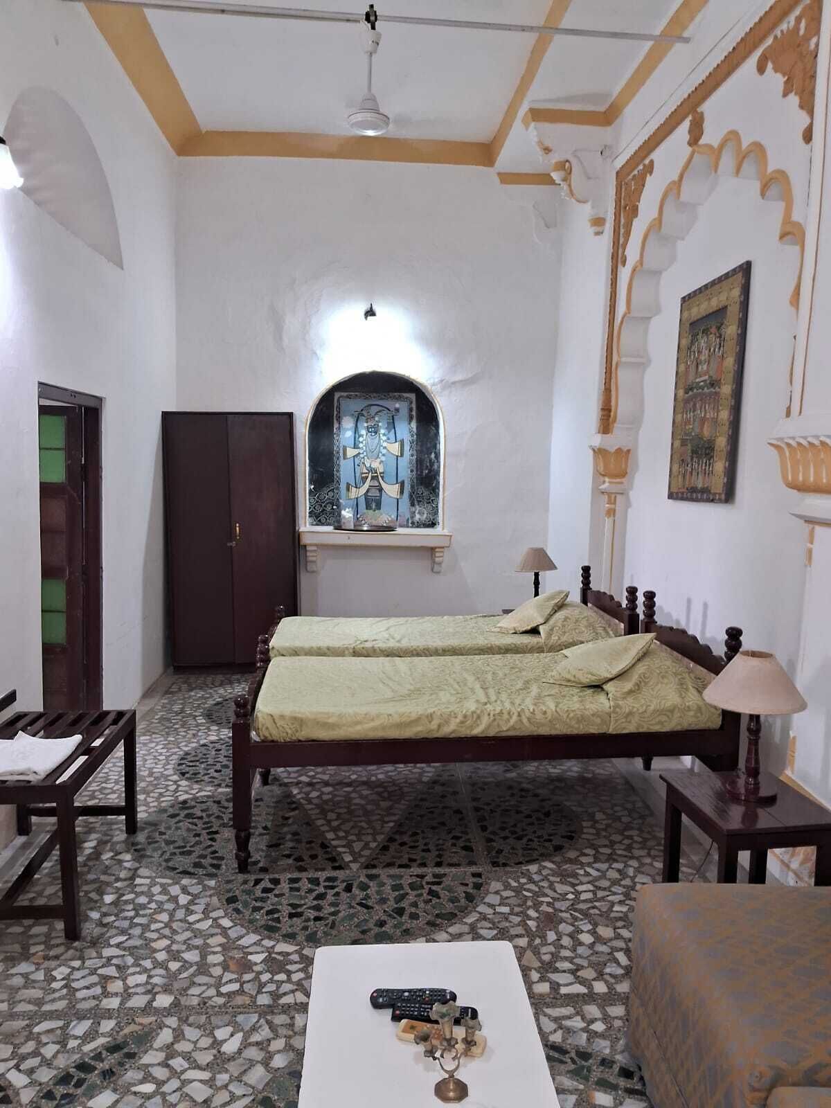 A room with a bed, a desk, a wardrobe, and a decorative alcove with a framed artwork.