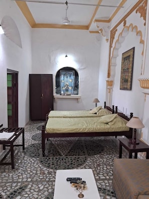 A room with a bed, a desk, a wardrobe, and a decorative alcove with a framed artwork.