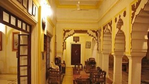 A traditional room with a long corridor, wooden furniture, and ornate architectural details. - Roopangarh Fort  (Roopangarh)