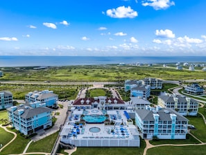 Ein Resort mit mehreren Gebäuden, einem zentral gelegenen Poolbereich und Blick auf den Ozean.