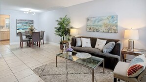 A living room with a sofa, coffee table, and a painting on the wall. - The Jefferson 222 - St Pete (St. Petersburg)