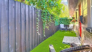 A patio with artificial grass, wicker furniture, and a wooden fence. - The Jefferson 222 - St Pete (St. Petersburg)