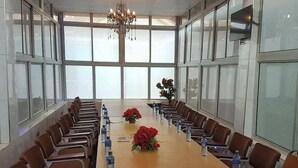 A conference room with a long table, chairs, water bottles, and a chandelier.