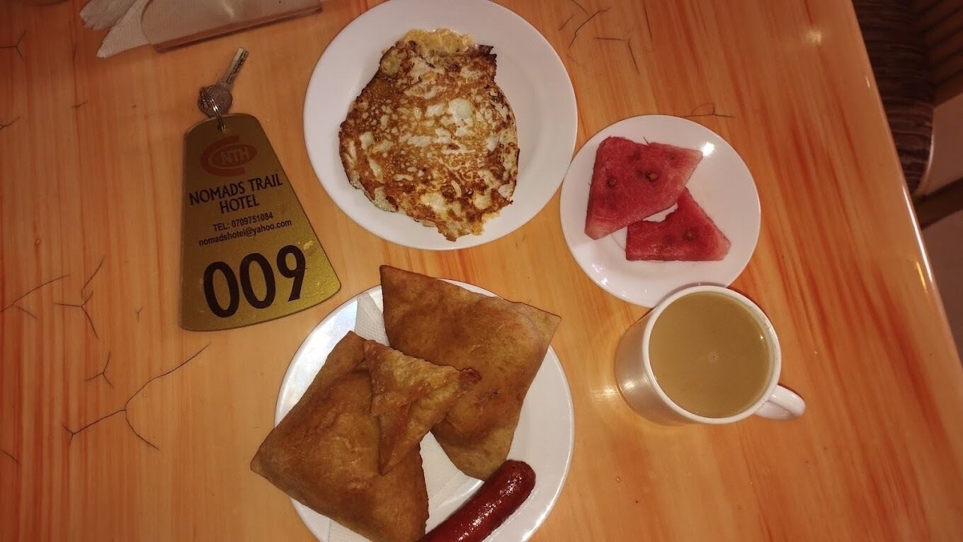 Ett bord med en tallrik med samosas, en tallrik med vattenmelon, en tallrik med omelett och en kopp te.