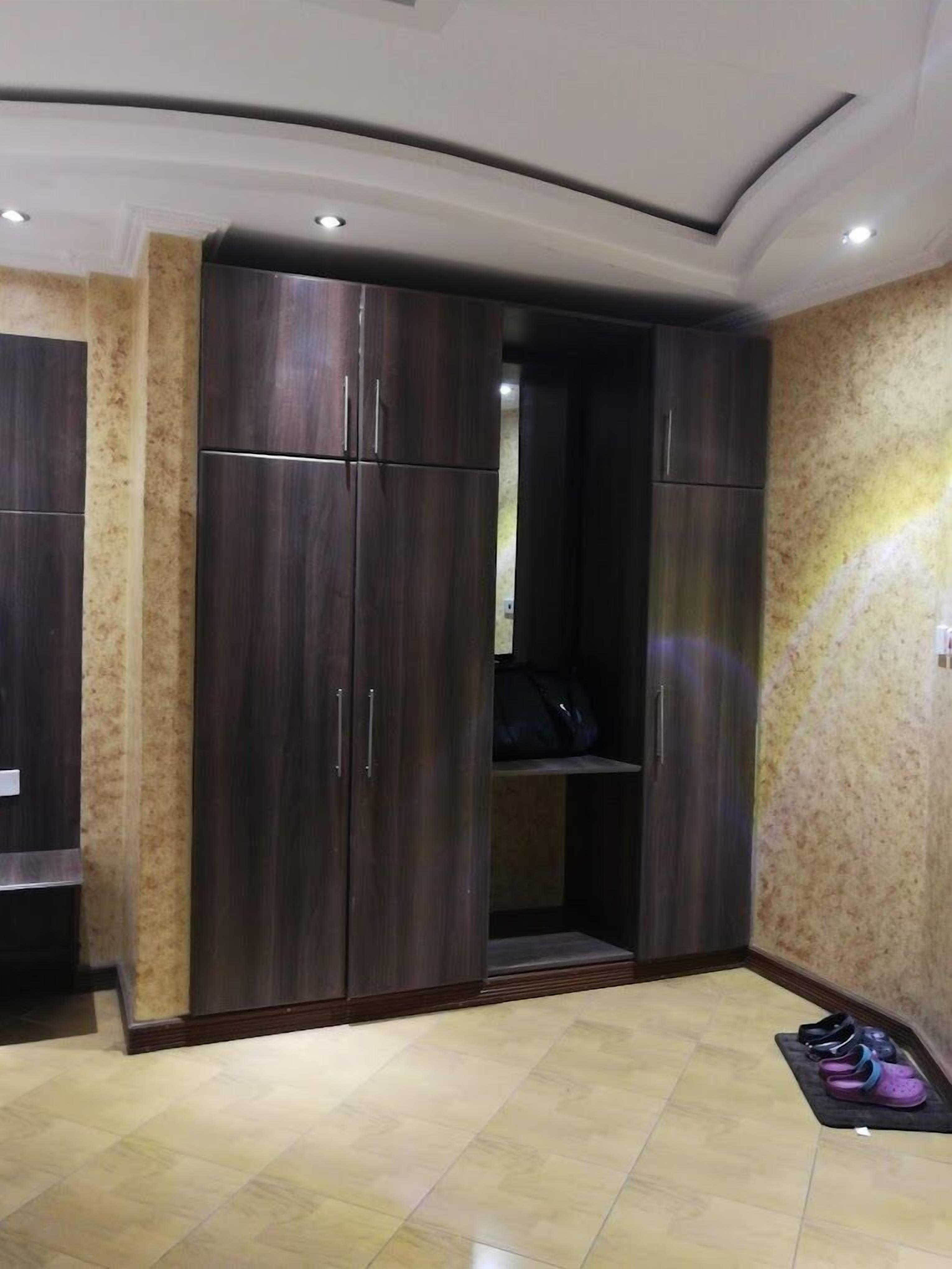 A room with a large wardrobe, a mirror, and a pair of slippers on the floor.