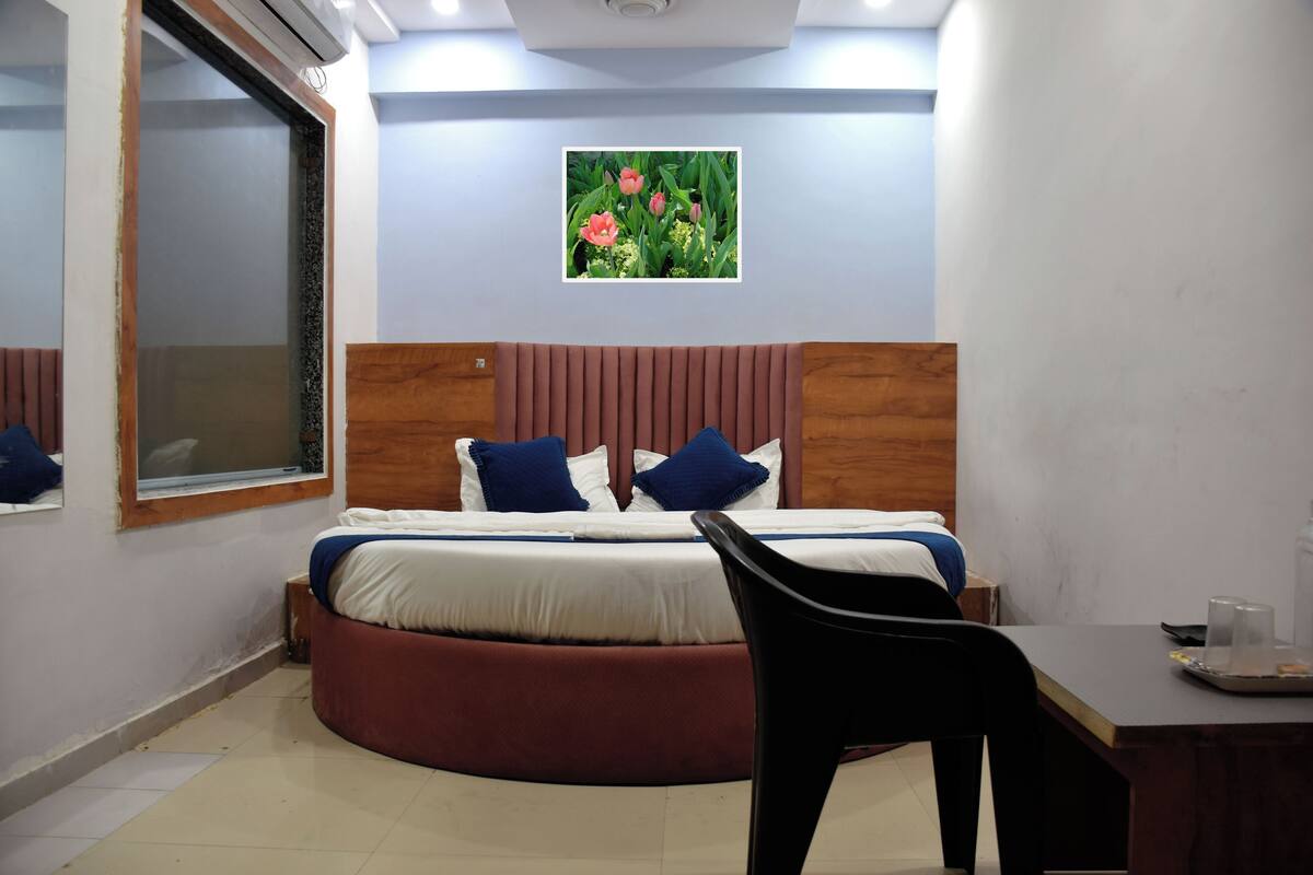 Una habitación de hotel con una cama, un escritorio, una silla, una ventana y un cuadro en la pared.