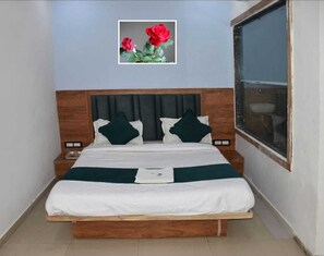Uma cama bem arrumada com cabeceira de madeira, um quadro com flores na parede e uma janela do lado direito.
