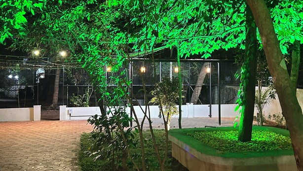 A paved walkway with a tree-lined path, a fenced area, and string lights. - Tranquil bed & breakfast with AC in Aluva (Aluva)