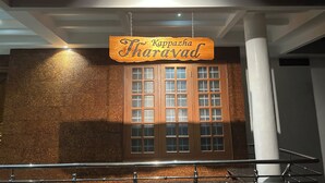 A wooden sign with the name "Kappazha Thoreavad" hanging above a door with multiple windows. - Tranquil bed & breakfast with AC in Aluva (Aluva)