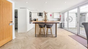 Cozinha moderna com piso em padrão herringbone, uma ilha central com bancos e uma porta de vidro deslizante para um alpendre.