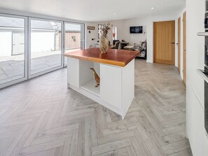 A modern kitchen with a wooden countertop, a herringbone floor, and a sliding glass door leading to a patio. - 3 bedroom accommodation in Falmouth (Falmouth)