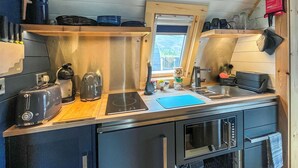 Cocina compacta con tostadora, hervidor, placa de inducción, pileta y lavavajillas.