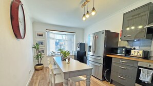 A modern kitchen with a dining area, wooden flooring, and a large window with blinds. - 2 bedroom accommodation in Peacehaven (Peacehaven)