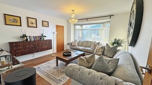 A living room with a sofa, coffee table, and a wooden cabinet. - 2 bedroom accommodation in Peacehaven (Peacehaven)