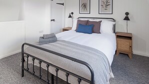 Un dormitorio con una cama, mesitas de noche, una puerta y dos lámparas de pared.