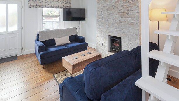 Una sala de estar con pared de piedra, chimenea, sofá y televisor.
