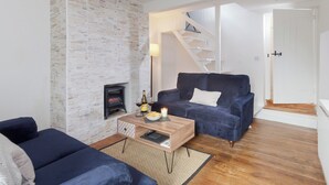 Una sala de estar con pared de piedra, chimenea, sofá, mesa de centro y escalera.