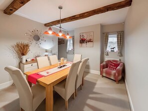 A dining area with a wooden table, six chairs, a red placemat, and a pendant light fixture. - 2 bedroom accommodation in Hinton, Market Drayton. (Hinton, Market Drayton.)