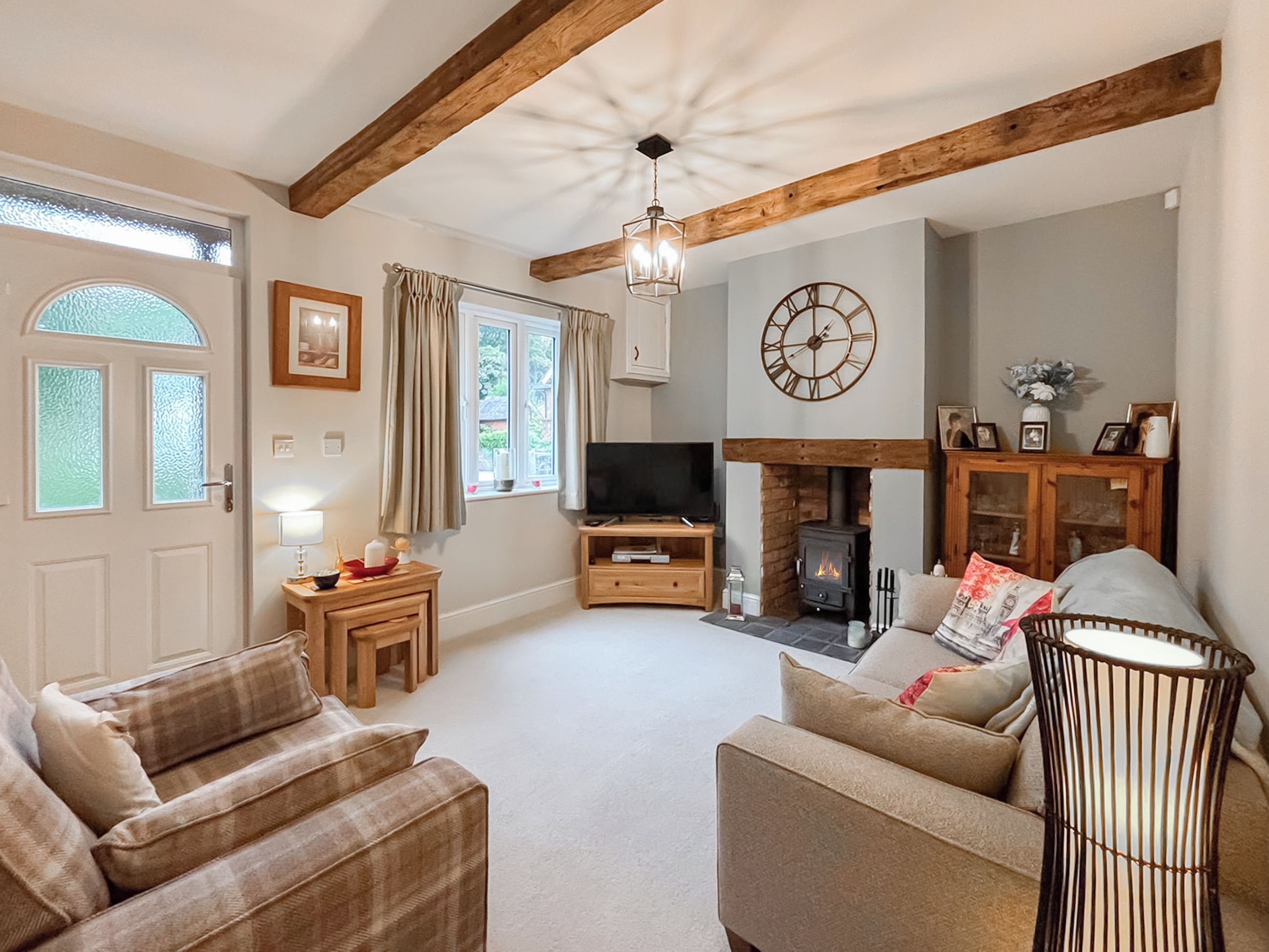 A cozy living room with a fireplace, wooden beams, a television, and comfortable seating.