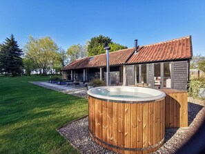 Une maison moderne dotée d’un jacuzzi, d’une terrasse en bois et d’un espace patio.