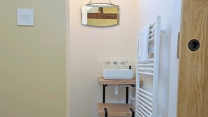 Une salle de bain avec un lavabo blanc, un meuble-lavabo en bois, des carreaux de sol à motifs, un miroir et un porte-serviettes.