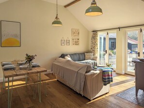 Une pièce chaleureuse avec une table à manger en bois, un canapé et une grande fenêtre.