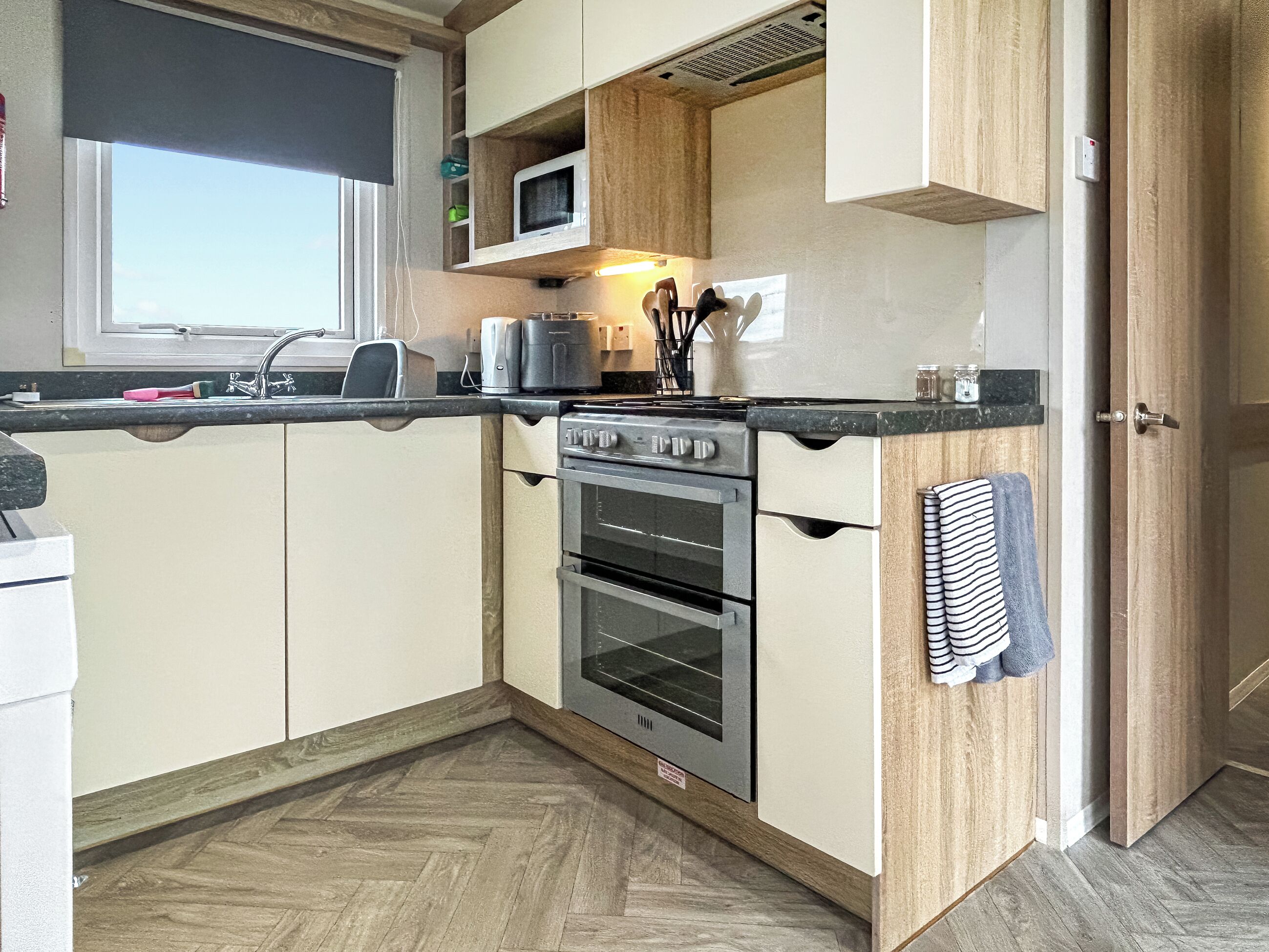 A compact kitchen with a built-in microwave, a stove, and a sink.