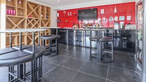 A bar area with stools, a TV mounted on the wall, and shelves with bottles. - 6 bedroom accommodation in Llandevaud (Llandevaud)