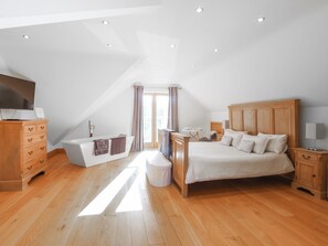 A bedroom with a wooden bed, a wooden dresser, a white vanity, and a television on a dresser. - 6 bedroom accommodation in Llandevaud (Llandevaud)