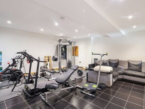 A home gym with exercise equipment, a couch, and a tiled floor.
