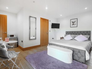 A bedroom with a bed, a TV, a mirror, a wooden door, and a microwave. - 6 bedroom accommodation in Llandevaud (Llandevaud)