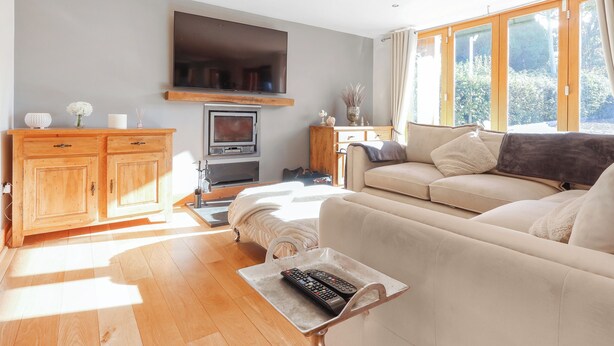 A living room with a sofa, TV, wooden cabinet, and a fireplace. - 6 bedroom accommodation in Llandevaud (Llandevaud)