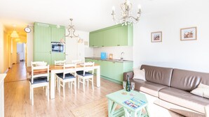 En moderne stue med spiseområde, et tekøkken og en brun lædersofa.