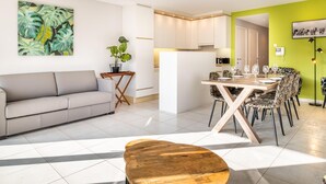 A modern living room with a grey sofa, a wooden coffee table, and a dining area with a wooden table and patterned chairs. - Modernly furnished flat in St-Idesbald (Sint-Idesbald)