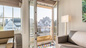 A modern living room with a sliding glass door leading to a balcony, a beige sofa, and a colorful mat on the floor. - Modernly furnished flat in St-Idesbald (Sint-Idesbald)