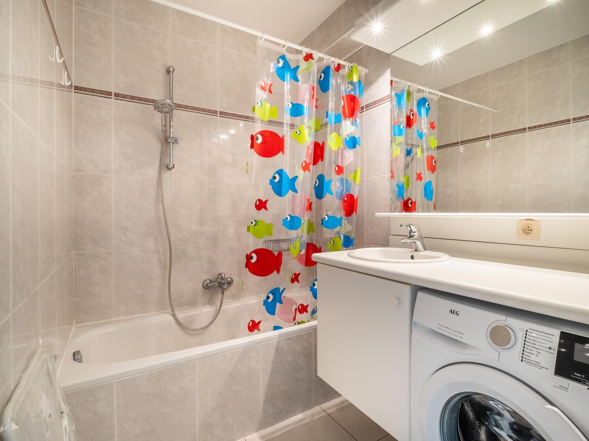 Een moderne badkamer met een badkuip, douche en een wasmachine.
