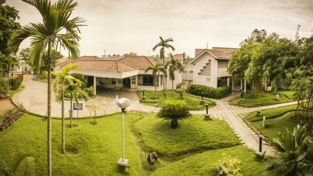 Un barrio residencial con una casa, césped cuidado y algunas palmeras.