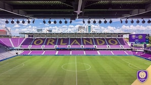 Een leeg stadion, met 'ORLANDO' op de stoelen, en een helder uitzicht op de stadshemel.