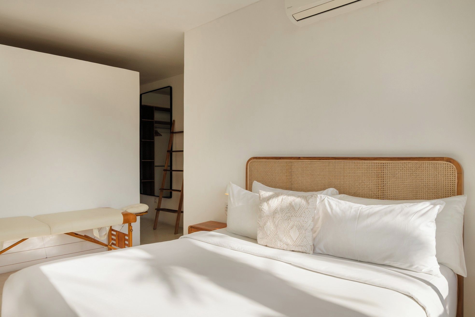 A bedroom with a bed, a chair, and a ladder against the wall.