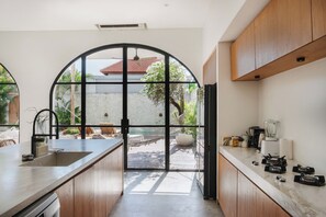 Une cuisine moderne dotée d’une grande fenêtre en arc de cercle, de meubles en bois et d’un plan de travail agrémenté d’appareils de cuisine.