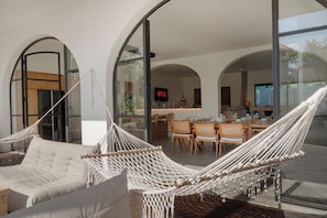 A modern interior with a hammock, a sofa, and a dining area with chairs and a table. - Bianca Villa by Betterplace (Canggu)