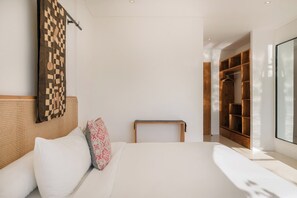 A modern bedroom with a large bed, a wooden headboard, a bedside table, a hanging artwork, and a walk-in closet. - Bianca Villa by Betterplace (Canggu)