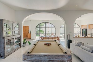 A spacious living area with a pool table, a sofa, and a dining table set for four. - Bianca Villa by Betterplace (Canggu)