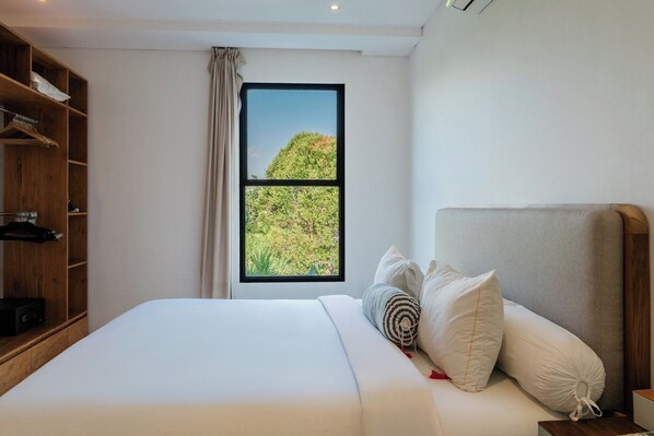 Une chambre d’hôtel avec un lit, une armoire et une fenêtre donnant sur un paysage verdoyant.